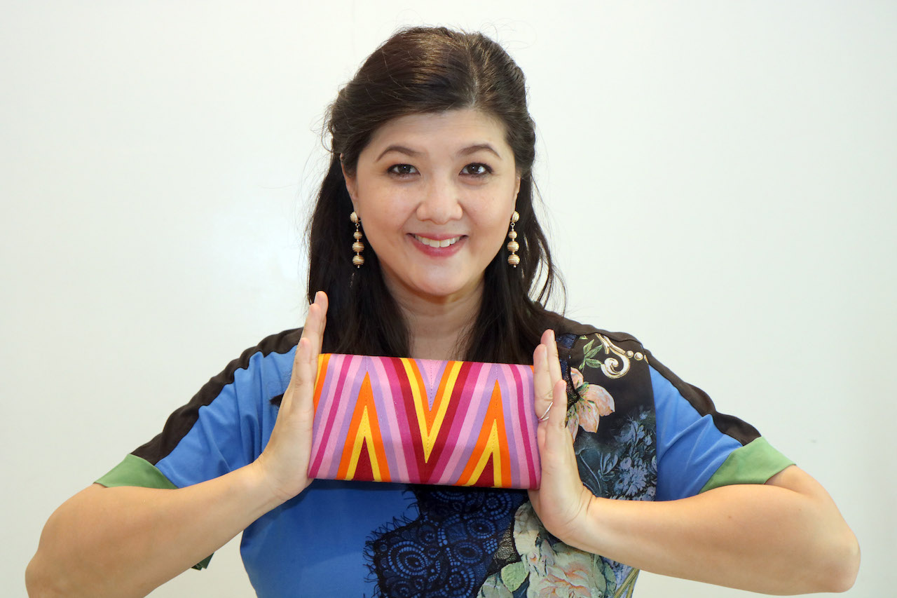 Alumna Carissa Evangelista with a colorful bag from her collection