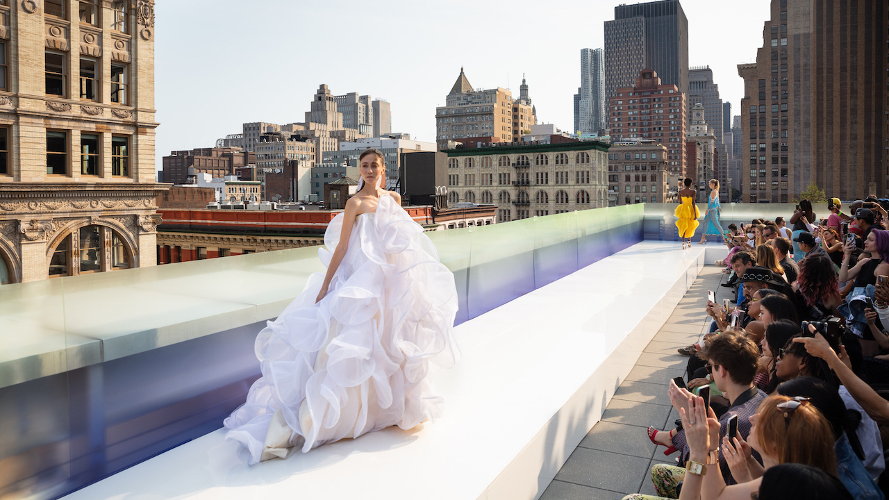 An ethereal dress designed by FIDM Grad Kyle Denman appears on an outdoor runway at New York Fashion Week