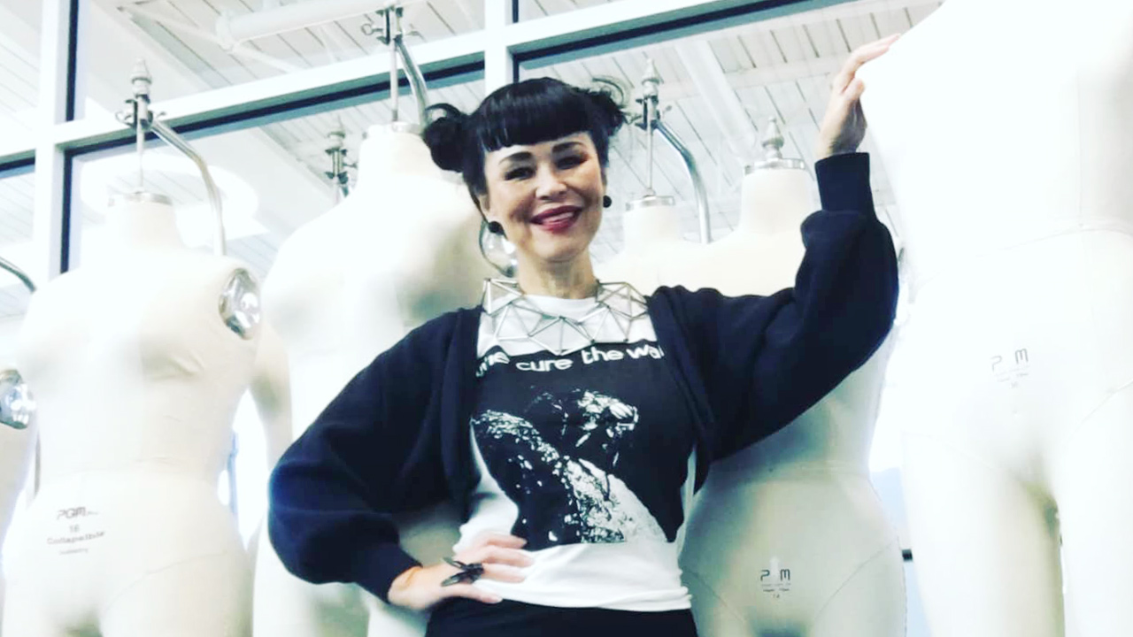 Educator Stephanie Chase poses in front of a rack of mannequins