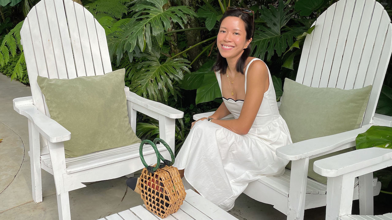 A portrait of FIDM Grad Anika Martirez Ang seated on a white Adirondack chair