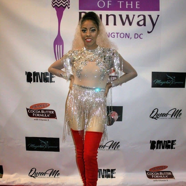 Grad Danelle Johnson poses on the red carpet in a sparkling outfit with red thigh high boots