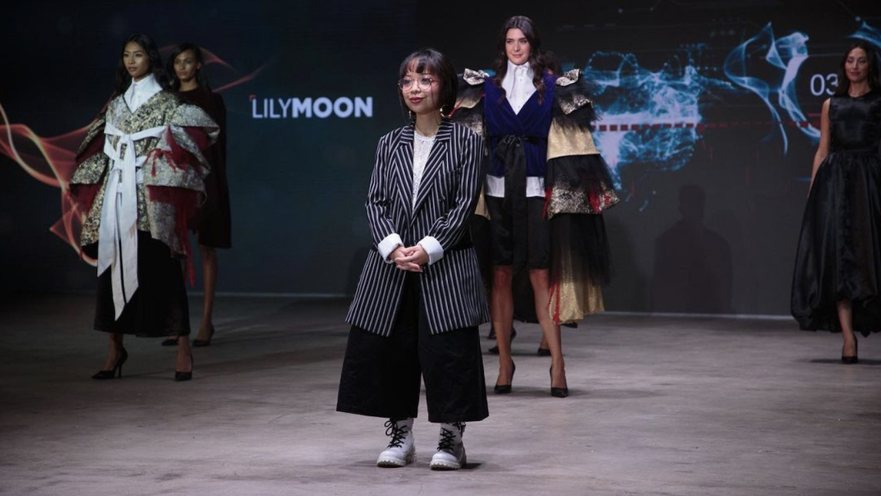 Grad Lilymoon Perez stands on the runway with models wearing her collection at Vancouver Fashion Week