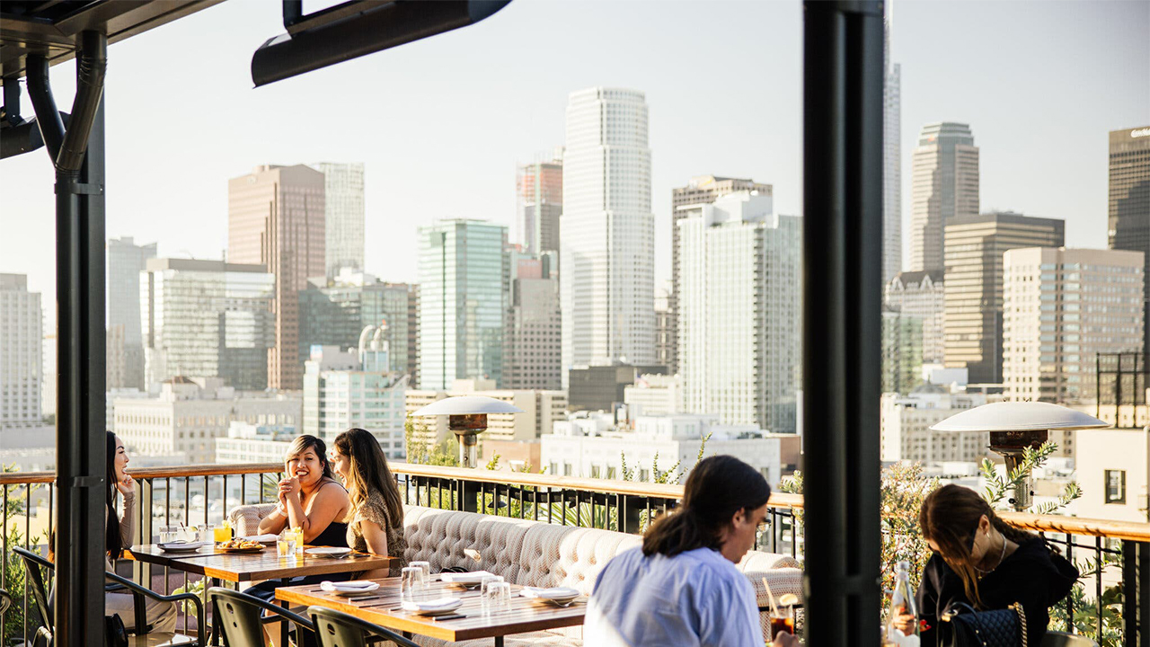 Photo of Los Angeles skyline from the balcony of a restaurant with diners at a few tables