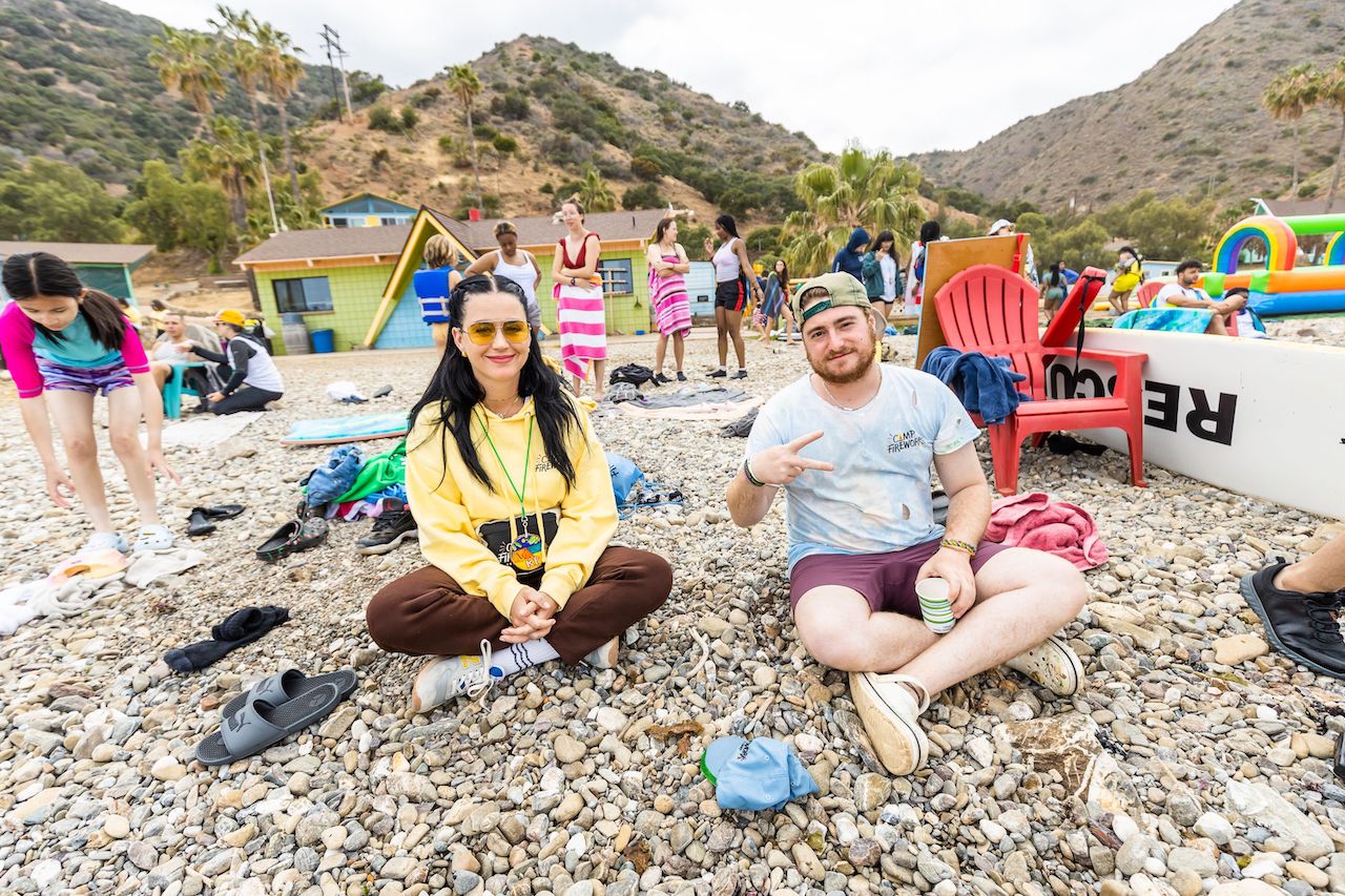 Camp Firework founder Katy Perry sits on a beach near campers