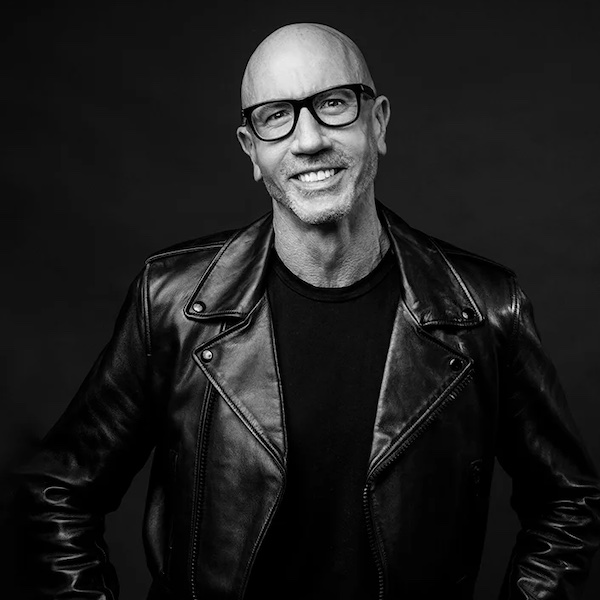 A black and white portrait of FIDM Grad Ron Thurston who is smiling and wearing glasses