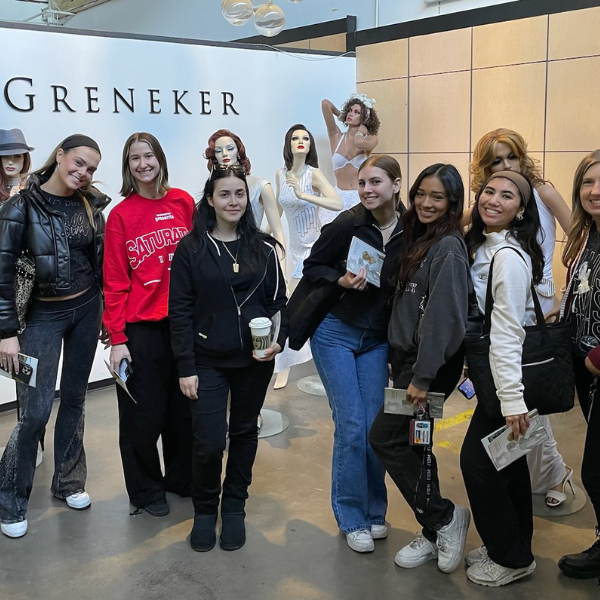 7 FIDM students stand among 3 mannequins indoors at Greneker mannequin house in Los Angeles
