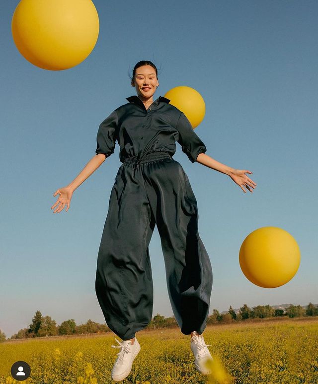 model jumping outside with yellow balloons
