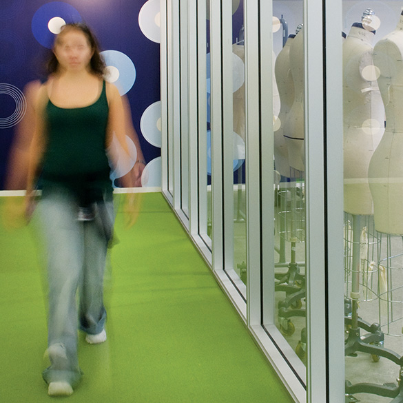 Student walking down a green hallway outside of a fashion design classroom
