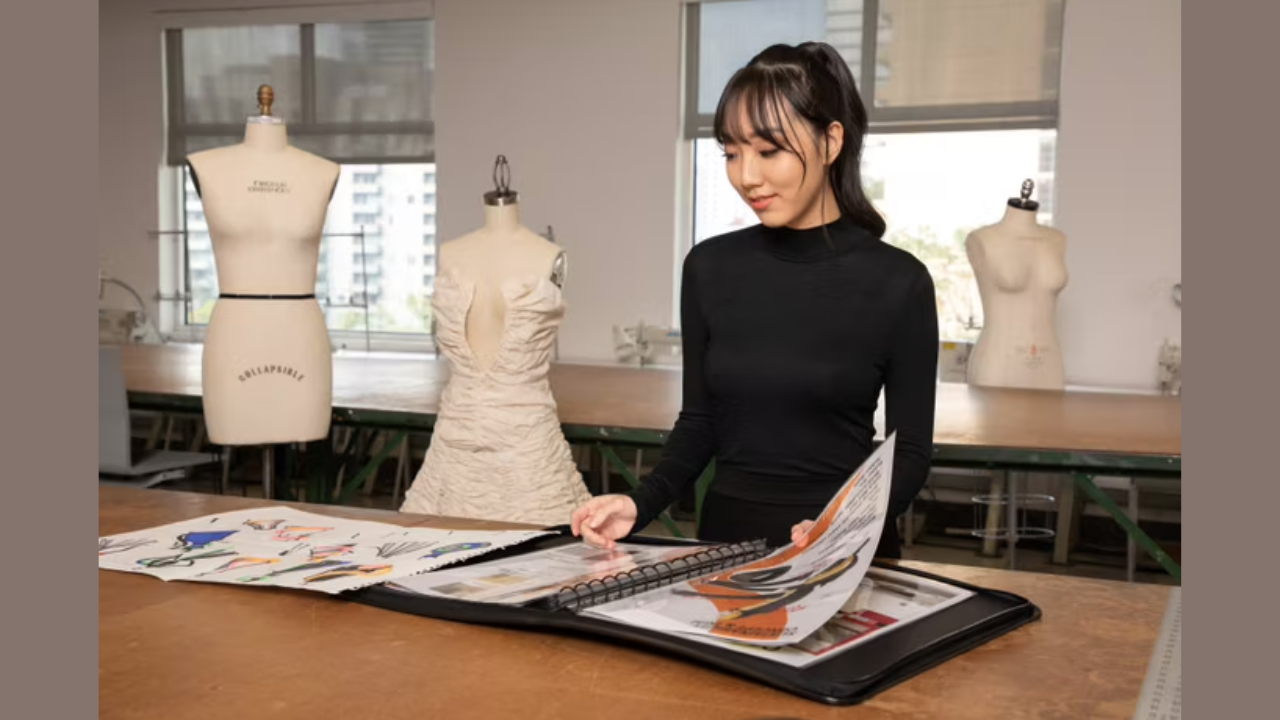 HyeRin Lee fashion design student wearing black long sleeve top looking through a portfolio