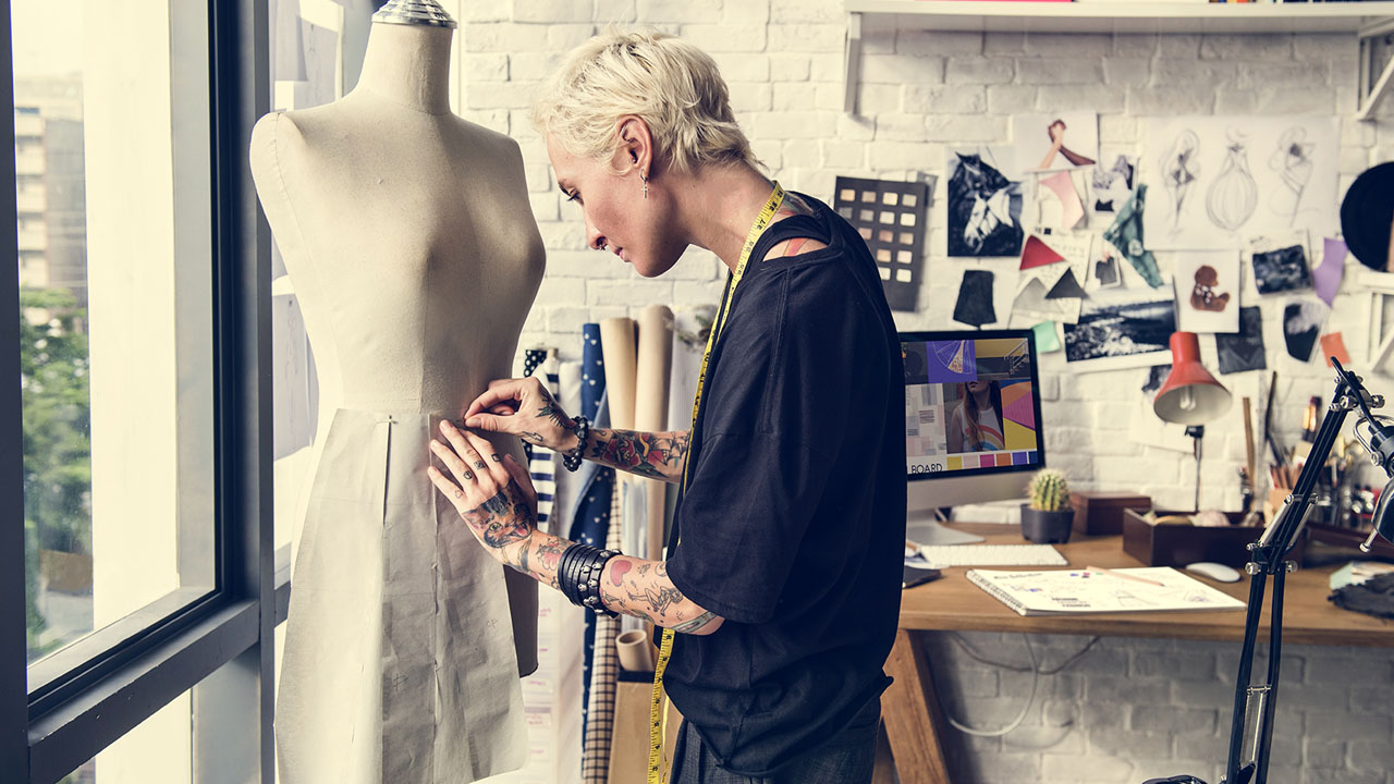 Fashion designer pinning drapery to a form next to her studio window