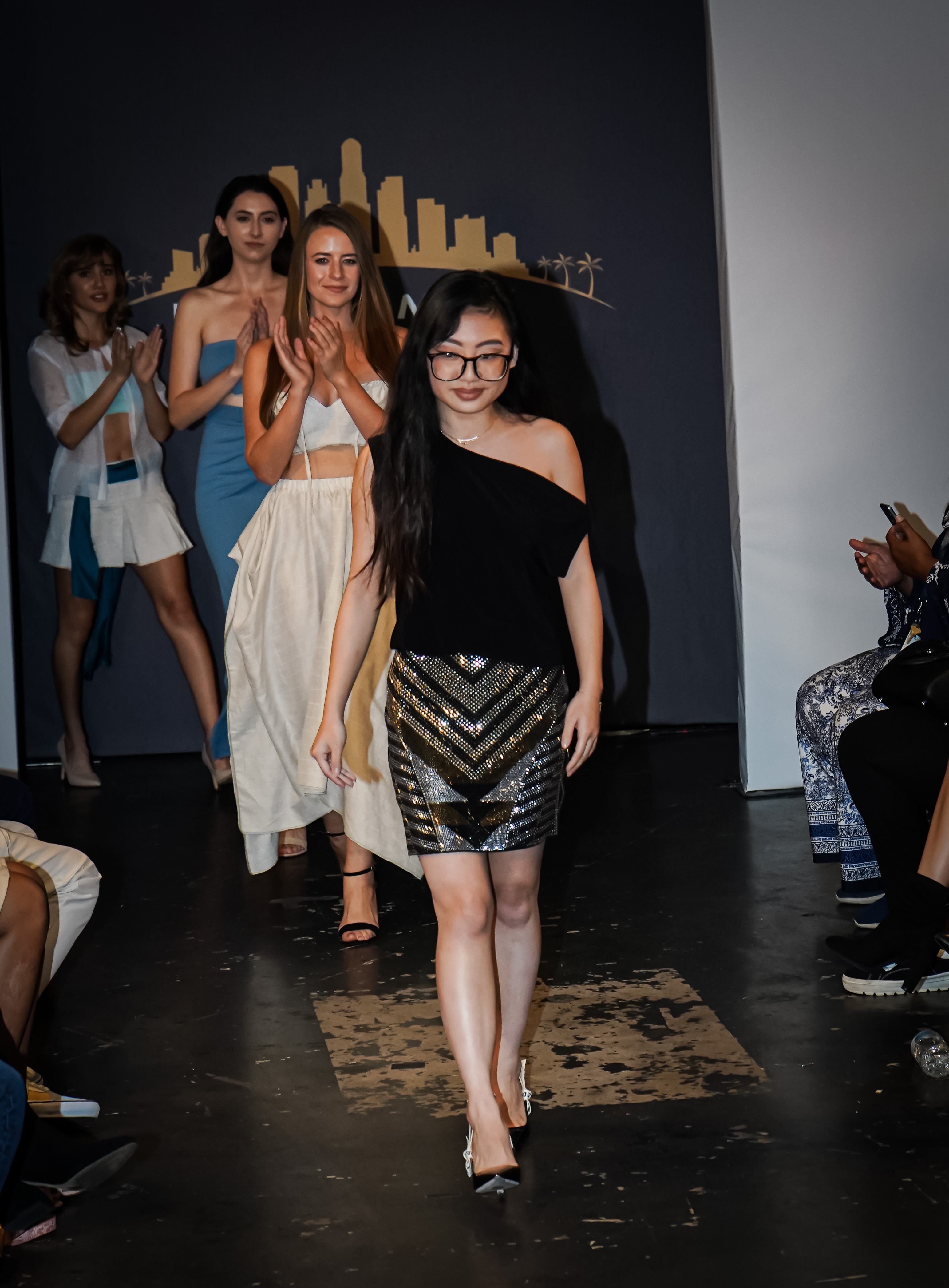 FIDM Student Celeste Tran on the runway with models wearing her fashion designs