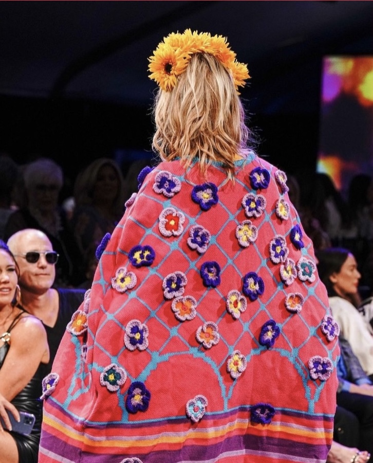 Sofia Masuda fashion design cape in bright orange, pink, blue, and yellow crocheted flowers photographed from the back