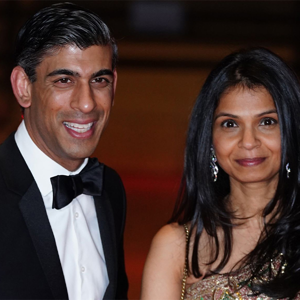 Rishi and Akshata are side by side at an event. He's in a tuxedo, and she's in a champagne colored beaded dress with her dark hair over her shoulders.