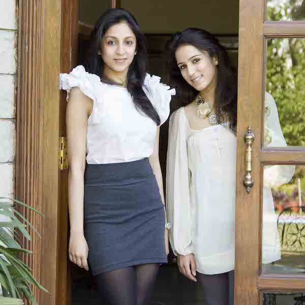 Sisters and FIDM Grads Radhika Mittal and Madhvi Pittie stand in a wooden doorway