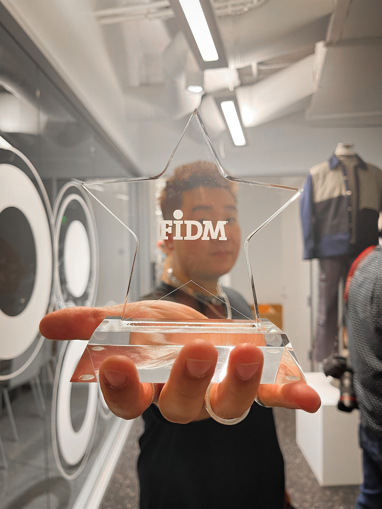 FIDM Grad Colin Huang holds a clear star emblazoned with FIDM to the camera
