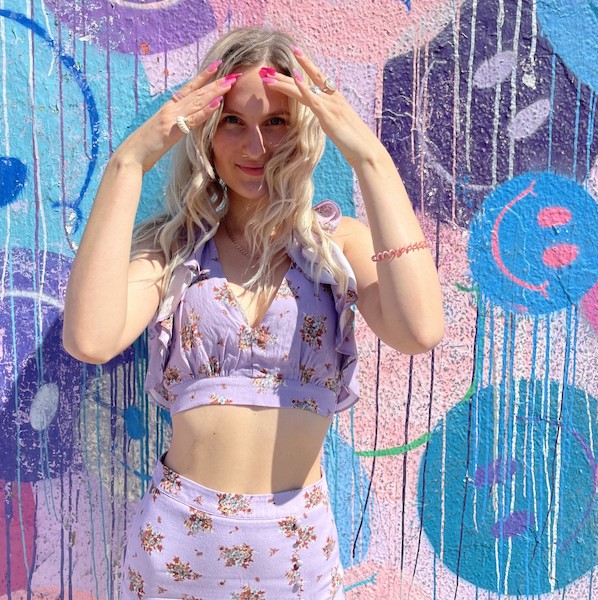 FIDM Student Danijela Vasic poses in front of a colorful wall mural