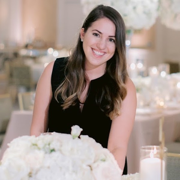 Award-winning wedding planner Whitney Bailey poses next to a flower-filled table